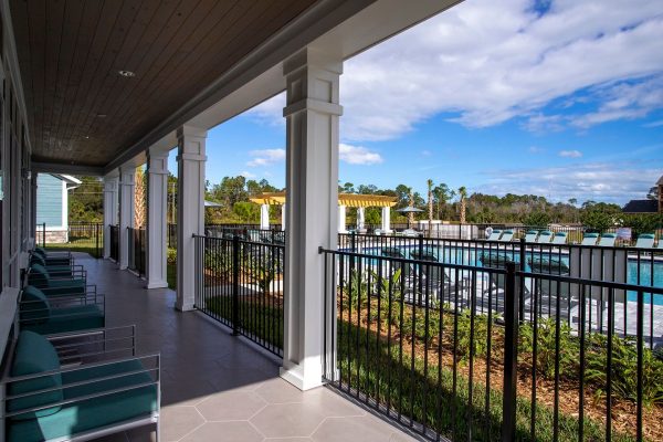 View of the pool from the clubhouse porch which offers shaded lounge seating and a short path down to the pool deck