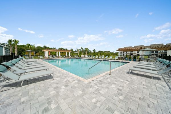 Sparkling blue pool with ample poolside lounge seating and shaded seating under the pergola